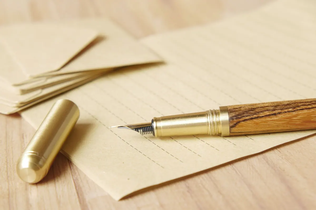 Caneta-tinteiro sobre envelopes e documentos em mesa de madeira, em ambiente sóbrio